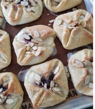 Freshly baked pastries topped with sliced almonds and fruit filling.