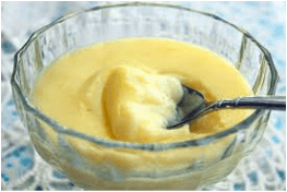 Creamy custard being scooped from a glass bowl.