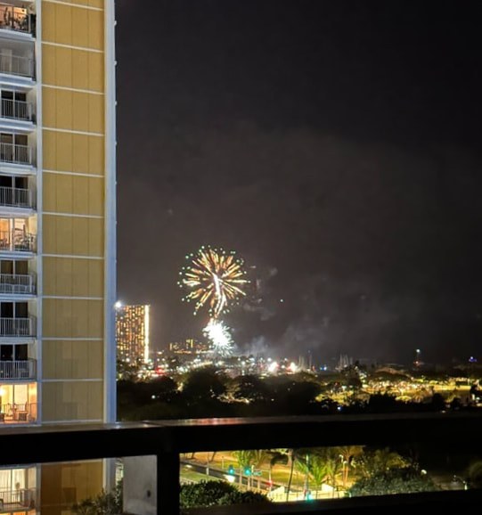Fireworks lighting up the night sky near city buildings.