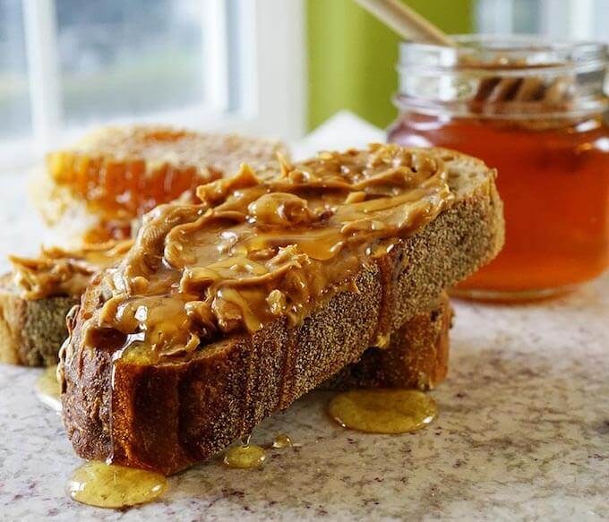 Slice of bread topped with peanut butter and honey drizzle.