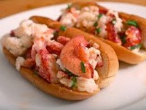 Two lobster rolls filled with lobster meat and herbs.