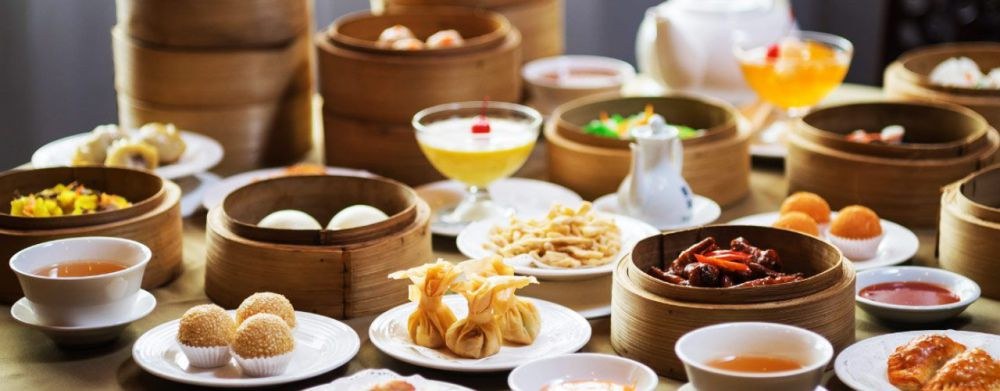 A table full of assorted Chinese dim sum dishes and tea.