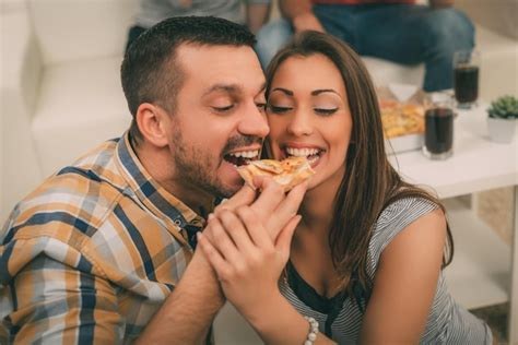 A happy couple sharing a slice of pizza together.