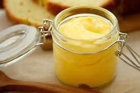 A jar of creamy, yellow homemade butter on a wooden board.