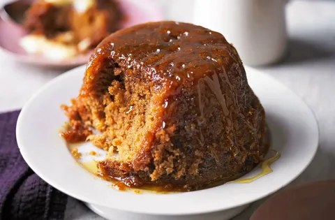 Sticky toffee pudding with caramel sauce on a white plate.