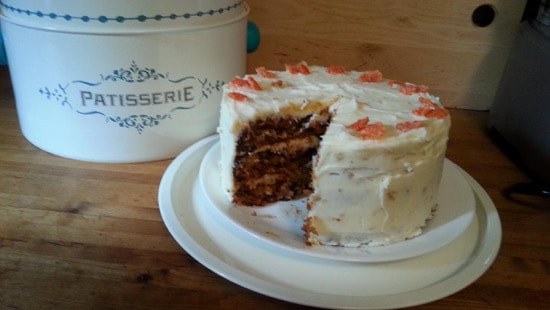 Homemade layered chocolate cake with white frosting and red sprinkles.