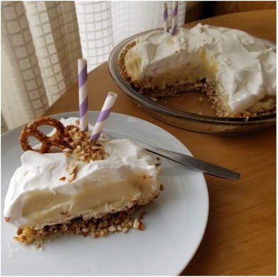 Slice of creamy pie with pretzel crust and whipped topping.