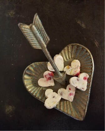 Heart-shaped dish with arrow and decorated heart candies.