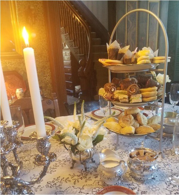 Elegant tea setup with tiered trays of pastries and lit candles.
