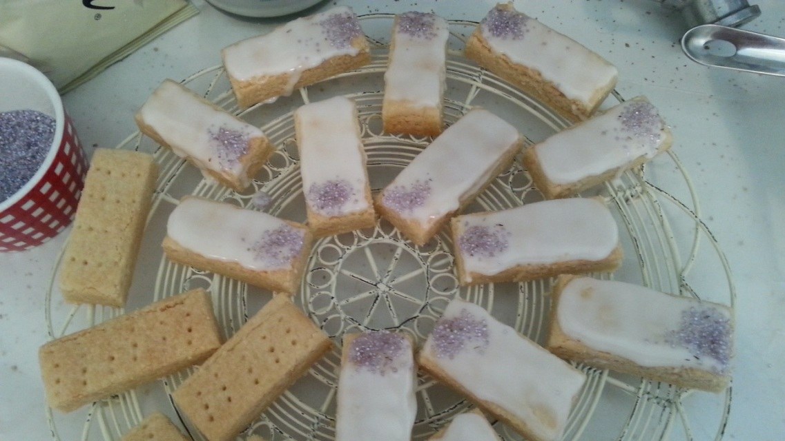 Frozen dessert bars with a crumbly base and purple topping on a cooling rack.