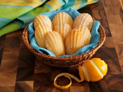 Golden madeleine cookies in a basket with a blue cloth.