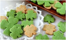 Green and beige shamrock-shaped cookies on a white doily.
