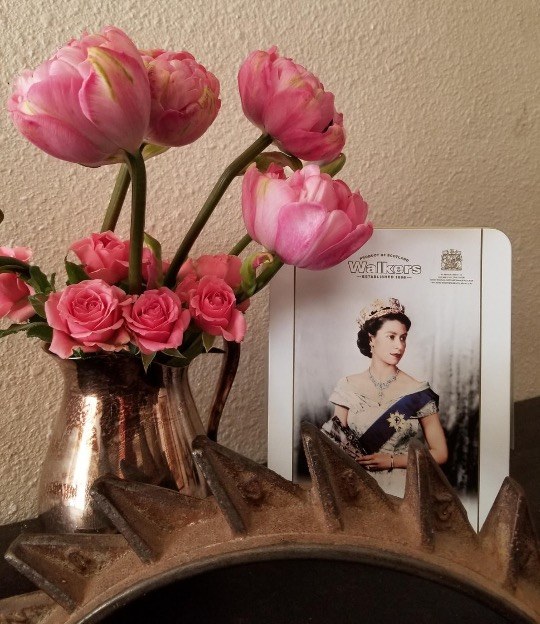 Pink flowers and a framed portrait on table.
