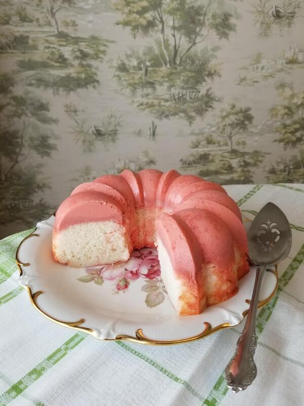 A slice of pink glaze-covered bundt cake on a floral plate.