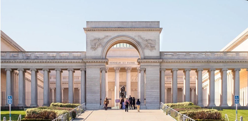Elegant stone archway with people walking through it on a sunny day.