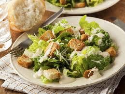 Fresh Caesar salad with croutons and grated cheese on a white plate.