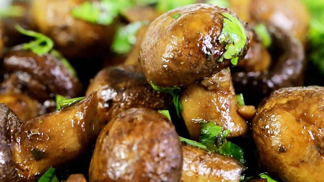 Close-up of fresh, brown mushrooms with green herbs.