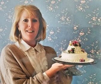 A woman holding a decorated cake with flowers.