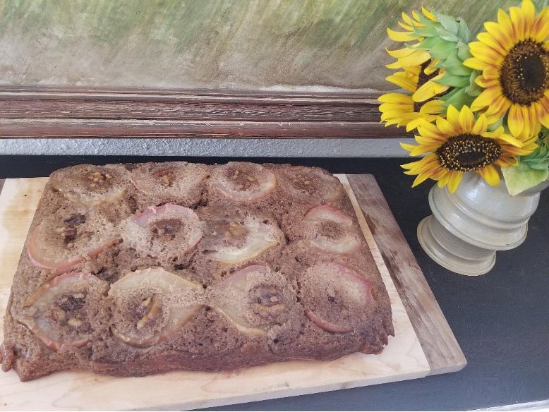 Homemade cake topped with pineapple slices on a wooden board.