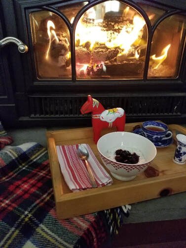 Cozy fireplace setup with snacks and a festive drink on a wooden tray.