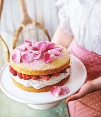 A layered cake with pink rose petals on top.