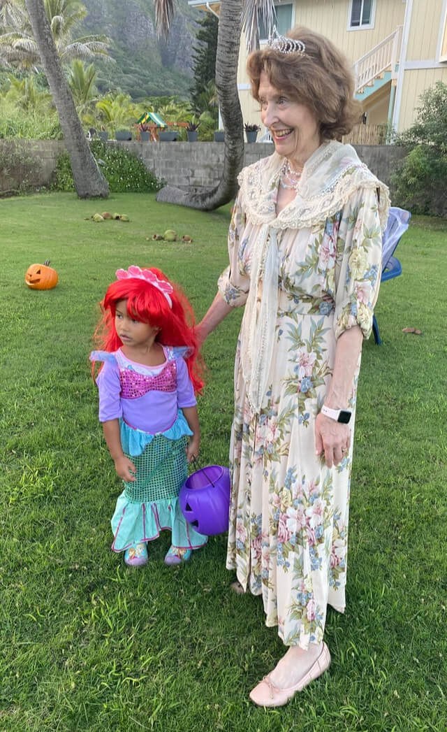 A child dressed as Ariel from The Little Mermaid with an adult in a floral dress.