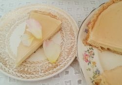 Slice of cheesecake with whipped cream and pear slices on a decorative plate.