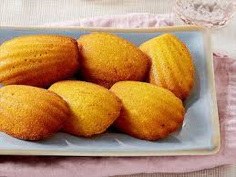 Golden-brown madeleine cookies on a white plate.