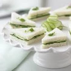 Elegant cucumber tea sandwiches on a white pedestal plate.