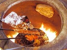 Traditional tandoor oven cooking kebabs and naan bread.