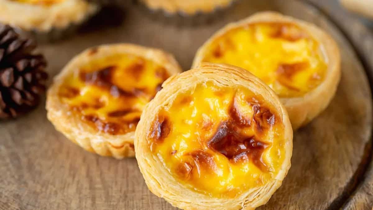 Close-up of three golden Portuguese egg tarts with flaky crusts.