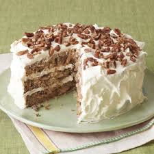 A tall layered cake with white frosting and pecan topping.