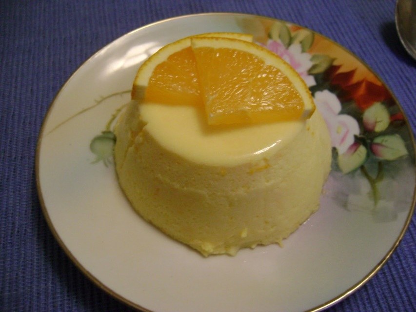 A creamy dessert topped with orange slices on a floral plate.