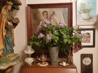 A cozy vintage room corner with flowers and framed pictures.