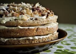 A close-up of a layered cake with creamy frosting and nut toppings.