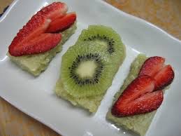 Slices of kiwi and strawberries on a creamy dessert.