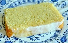 Slice of lemon-flavored sponge cake with creamy frosting on a decorative plate.