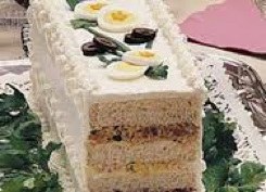 Sliced layered cake with cream and fruit toppings.