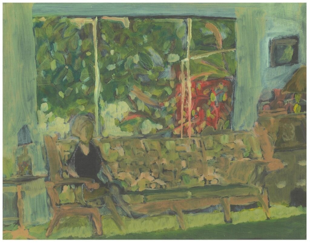 Person sitting on sofa near large window.