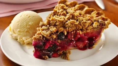 Slice of cherry crumble pie with vanilla ice cream.