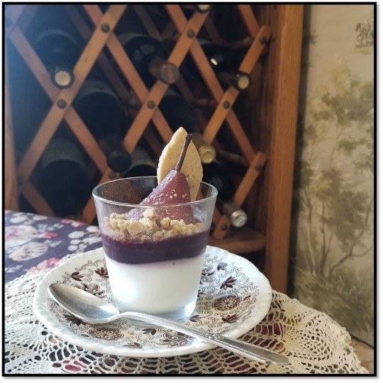 Dessert cup with berries and biscuit garnish.