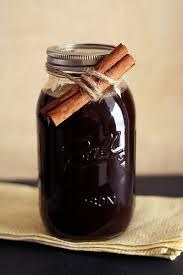 A mason jar filled with dark liquid and cinnamon sticks tied on top.