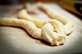 Uncooked twisted dough on a floured surface.