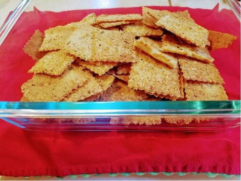 A glass container filled with golden, crispy square crackers.