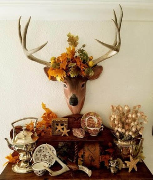 Decorative deer head with autumn flowers and rustic decor.