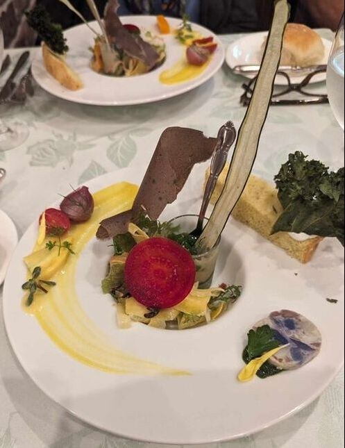 Gourmet dessert featuring a vibrant red sphere with chocolate and artistic garnishes.