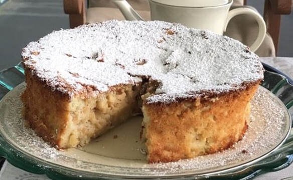 A slice of powdered sugar-topped cake on a plate.