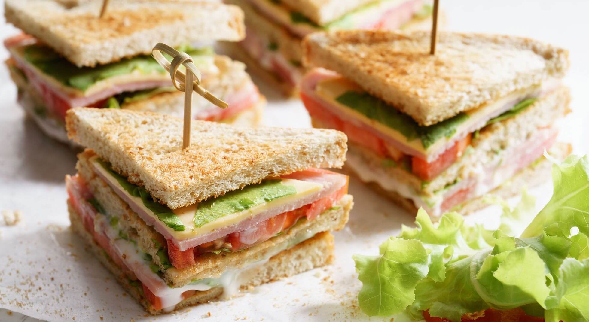 Stacked club sandwiches with layers of tomato, lettuce, and turkey.