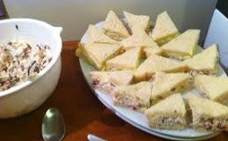 Plate of triangle-shaped sandwiches with filling on a table.