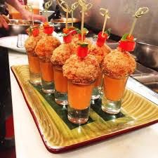 Gourmet appetizers served in shot glasses with crispy toppings and garnishes.